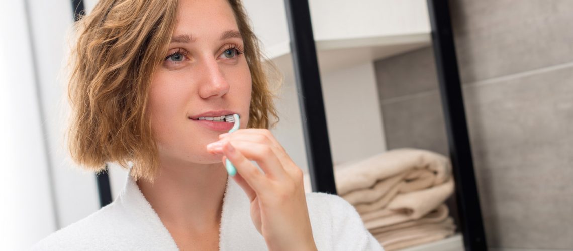 Young Beautiful Woman Brushing Her Teeth - gilbert dentists